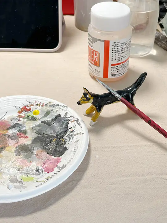 An artist hand-painting a small clay dog