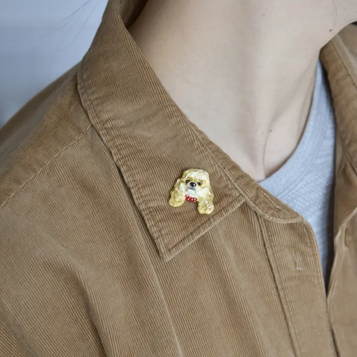 Clay dog portrait pin on a shirt collar