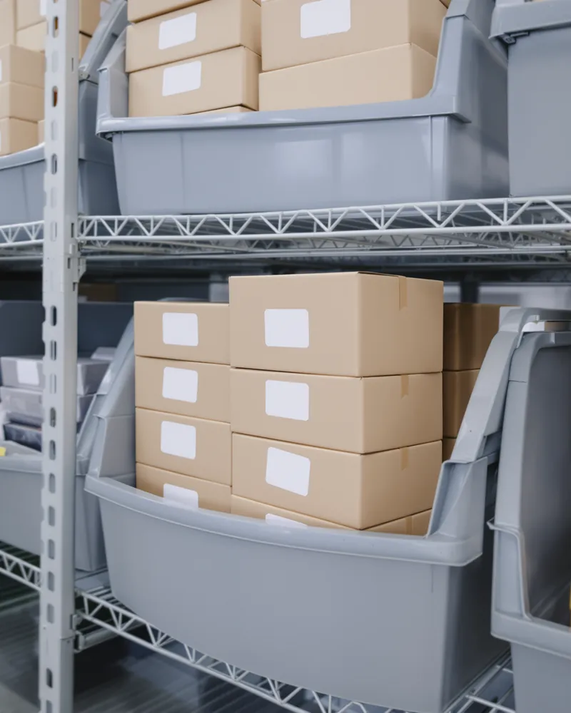 Cardboard boxes stacked in storage bins on shelves