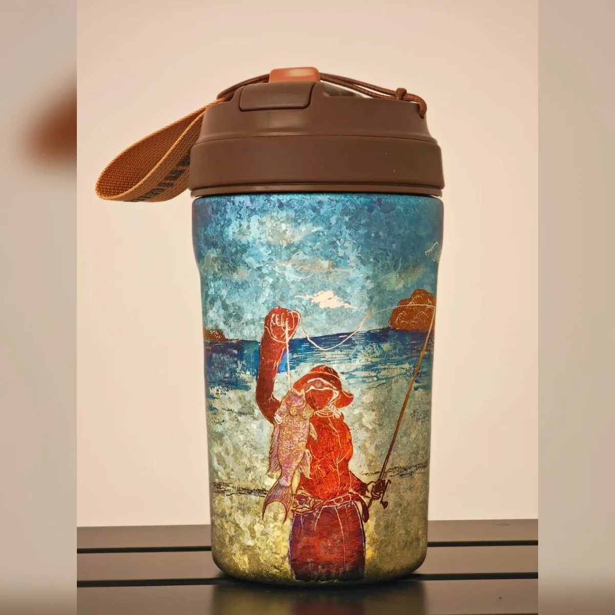 Travel tumbler painted with an angler holding a fish by the sea
