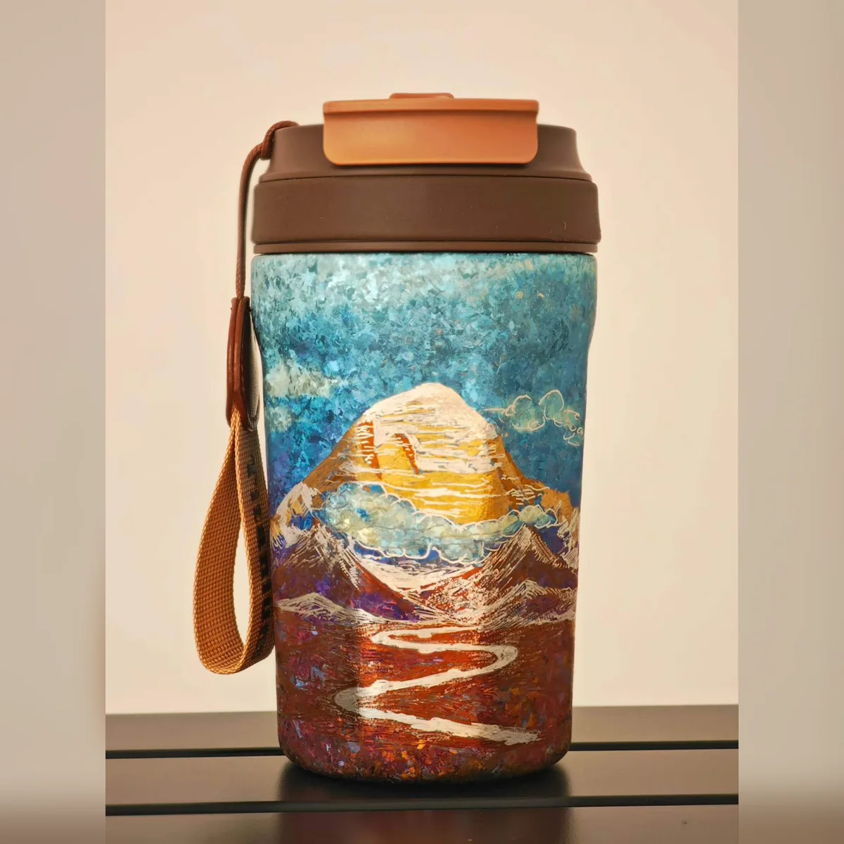 Travel tumbler painted with a golden peak and a winding river