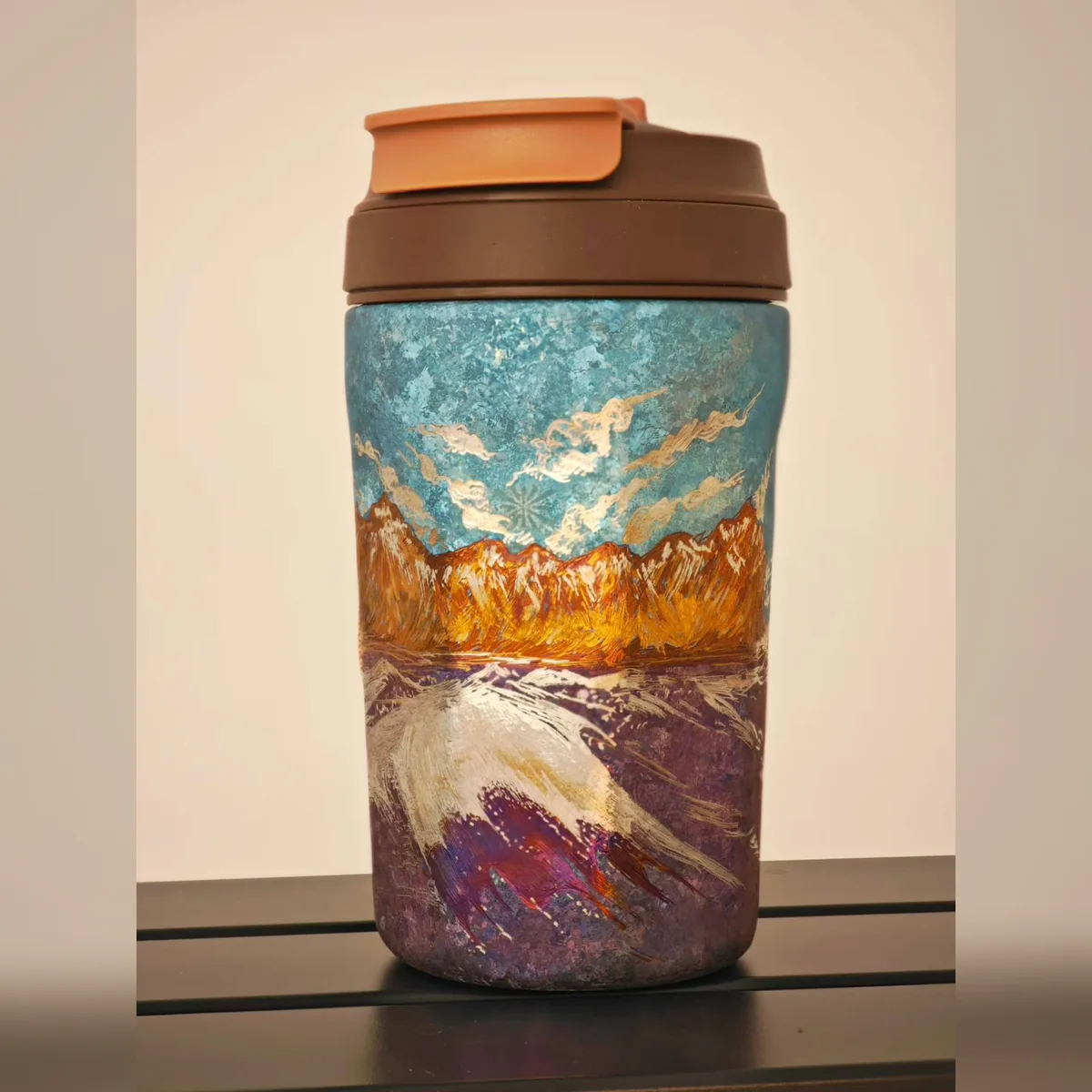 Travel tumbler painted with an orange sunset ridge